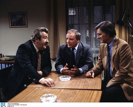 Foto: Kriminalobermeister Hans Brettschneider (WillyHarlander, links) und Kriminalkommissar LudwigLenz HelmutFischer, rechts) mit ihrem Vorgesetzten, Kriminalrat Schubert (RolfCastell), der sich in der "Tatort"-Episode "Im Fadenkreuz" (1981) über die Fortschritte der Untersuchungen Bericht erstatten lässt. Foto (Bildname: 21962-16-15) zur Verfügung gestellt vom Bayerischen Rundfunk (BR); Copyright BR/Foto Sessner