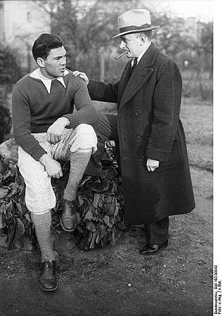 Boxweltmeister Max Schmeling mit seinem Manager, dem Amerikaner Joe Jacobs; Quelle: Deutsches Bundesarchiv, Digitale Bilddatenbank, Bild 102-09942; Fotograf: unbekannt / Datierung: unbekannt / Lizenz CC-BY-SA 3.0.