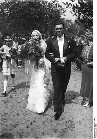 Boxweltmeister Max Schmeling und Anny Ondra am 6. Juli 1933 nach der kirchlichen Trauung; Quelle: Deutsches Bundesarchiv, Digitale Bilddatenbank, Bild 102-14813; Fotograf: unbekannt / Datierung: 1933 / Lizenz CC-BY-SA 3.0.