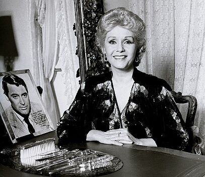 Portrait von Debbie Reynolds, aufgenommen 1986 in ihrem Heim in Los Angeles; Quelle: Wikipedia bzw. Wikimedia; Urheber: Allan Warren (britischer Fotograf; www.allanwarren.com); Diese Datei ist unter der Creative Commons-Lizenz Namensnennung-Weitergabe unter gleichen Bedingungen 3.0 Unported lizenziert. Es ist erlaubt, die Datei unter den Bedingungen der GNU-Lizenz für freie Dokumentation, Version 1.2 oder einer späteren Version, veröffentlicht von der Free Software Foundation, zu kopieren, zu verbreiten und/oder zu modifizieren; es gibt keine unveränderlichen Abschnitte, keinen vorderen und keinen hinteren Umschlagtext. Der vollständige Lizenztext ist im Kapitel GNU-Lizenz für freie Dokumentation verfügbar.