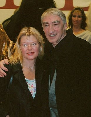 Gottfried John mit Ehefrau Barbara anlässlich der Deutschland-Premiere des Oliver Stone-Films "Alexander" im Kölner "Cinedom-Kino" (18.Dezember2004); Urheber: Stefan Servos; Lizenz:  CC-BY-SA-3.0; Quelle: Wikipedia bzw. Wikimedia Commons