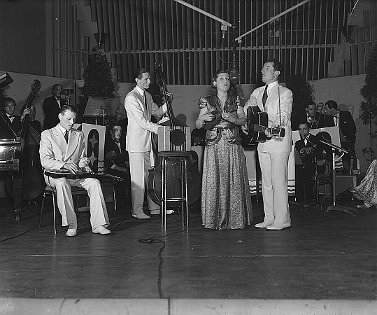 Die "Kilima Hawaiians" am 23. Januar 1946 bei ihrem Auftritt in dem Radio-Programm "De bonte dinsdagavondtrein"; v.l.n.r.: Theo Ehrlicher, Wim van Herpen, Mary Buijsman und Bill Buijsman; Rechteinhaber: Nationaal Archief1) (Den Haag, Rijksfotoarchief; Bestandsnummer: 901-4022); Urheber/Fotograf: Koos Raucamp / Anefo; Quelle: Wikimedia Commons; Lizenz: CC0 1.0 (Verzicht auf das Copyright)