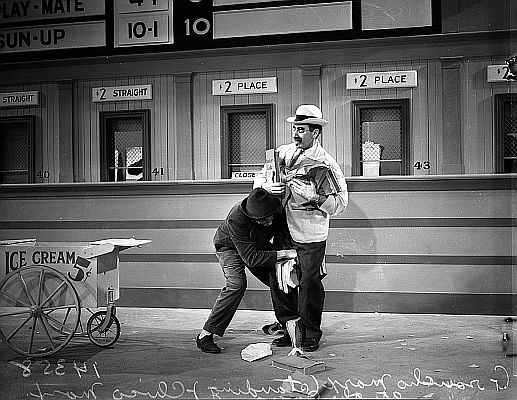Szenenfoto mit mit Groucho Marx (rechts) als Arzt Dr. Hugo Z. Hackenbush und Chico als Tony, der Fahrer des Sanatoriumsbusses, aus dem Film "Ein Tag beim Rennen" (1937); Quelle: Wikimedia Commons von "UCLA Library Digital Collection";Urheber: "Los Angeles Daily News"; Lizenz: CC BY 4.0 Deed