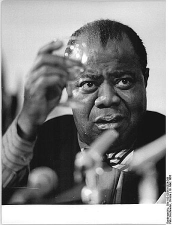 Louis Armstrong whrend einer Pressekonferenz am 19. März 1965 in Berlin; Quelle: Deutsches Bundesarchiv, Digitale Bilddatenbank, Bild 183-D0319-0024-011;  Fotograf: Christa Hochneder / Datierung: 19.03.1965 / Lizenz CC-BY-SA 3.0. 