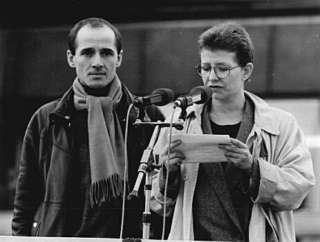 Johanna Schall und Ulrich Mühe sprechen bei der Berliner Großdemonstration am 4. November 1989; Quelle: Deutsches Bundesarchiv, Digitale Bilddatenbank, Bild 183-1989-1104-034; Fotograf: Hubert Link / Datierung: 4. 11.1989 / Lizenz CC-BY-SA 3.0.