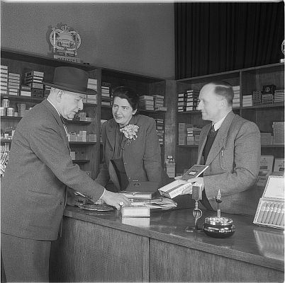 Die Schauspielerin Lori Leux bedient in einem Tabakwarengeschft gemeinsam mit dem Ladeninhaber einen Herren (Serie "Zwei Knstlerschicksale"); Urheber: Fritz Eschen (19001964); Datierung 1951; Originalfoto: DeutscheFotothek (file: df_e_0074866); Copyright SLUB Dresden/Deutsche Fotothek/Fritz Eschen; Quelle: deutschefotothek.de; Genehmigung zur Verffentlichung: 30.03.2017