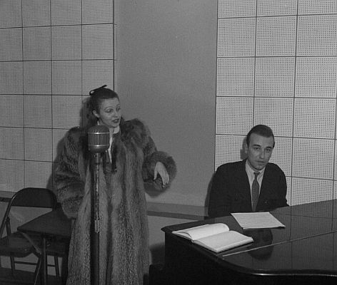 Elfie Mayerhofer 1948 vor dem Mikrophon im Aufnahmestudio des Senders "Rot-Wei-Rot" in Wien; am Klavier begleitet von Viktor Fit; Foto mit freundlicher Genehmigung der sterreichischen Nationalbibliothek (NB); Autor: United States Information Service  (USIS); Datierung: 29.11.1948; Copyright USIS/ ÖNB Wien; Bildarchiv Austria (Inventarnummer US 23.350)