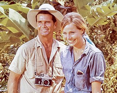 "Die Schurken von Bolivar (1968, "The Pink Jungle"): Szenenfoto mit James Garner als Modefotograf Ben Morris und Eva Renzo als das Model Alison Duquesne; mit freundlicher Genehmigung von Pidax-Film, welche die Agentenkomdie am 9. April 2021 auf DVD herausbrachte.