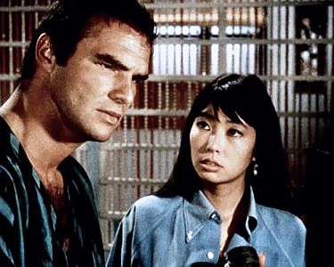 "Auf der Jagd nach dem verlorenen Gold": Szenenfoto mit Burt Reynolds als Abenteurer Pat Morrison und Miko Mayama als Mariko Riley; mit freundlicher Genehmigung von Pidax-Film, welche das Abenteuer Ende Februar 2022 auf DVD herausbrachte.