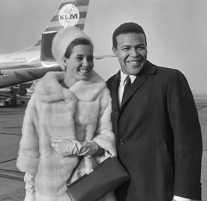 Chubby Checker mit Ehefrau Catharina am 23.12.1964 bei Ankunft auf dem Flughafen Amsterdam Schiphol; Rechteinhaber: Nationaal Archief�(Den Haag, Rijksfotoarchief; Bestandsnummer: 917-2719); Urheber/Fotograf: Joop van Bilsen / Anefo; Quelle: Wikimedia Commons: Lizenz: CC0 1.0 (Verzicht auf das Copyright)