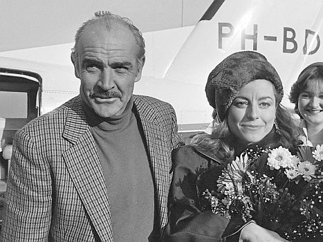 Sean Connery mit Ehefrau MichelineRoquebrunne am 23. November 1983 bei der Ankunft auf dem Amsterdamer Flughafen Schiphol; Rechteinhaber: Nationaal Archief (Den Haag, Rijksfotoarchief; Bestandsnummer: 932-7858); Urheber/Fotograf: Bogaerts, Rob / Anefo; Quelle: Wikimedia Commons; Lizenz: www.gahetna.nl/over-ons/open-data / CC BY-SA 3.0 NL