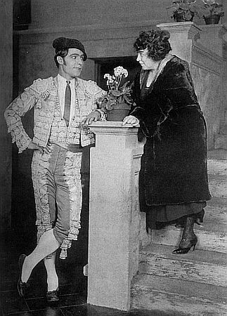 Rudolph Valentino und die Drehbuchautorin June Mathis (1892–1927) anlässlich der Drearbeiten zu dem von Fred Niblo in Szene gesetzten "Stummfilm "Blut und Sand" (1922); Urheber: Paramount Pictures Publicity; Quelle: Wikimedia Commons; Lizenz: gemeinfrei